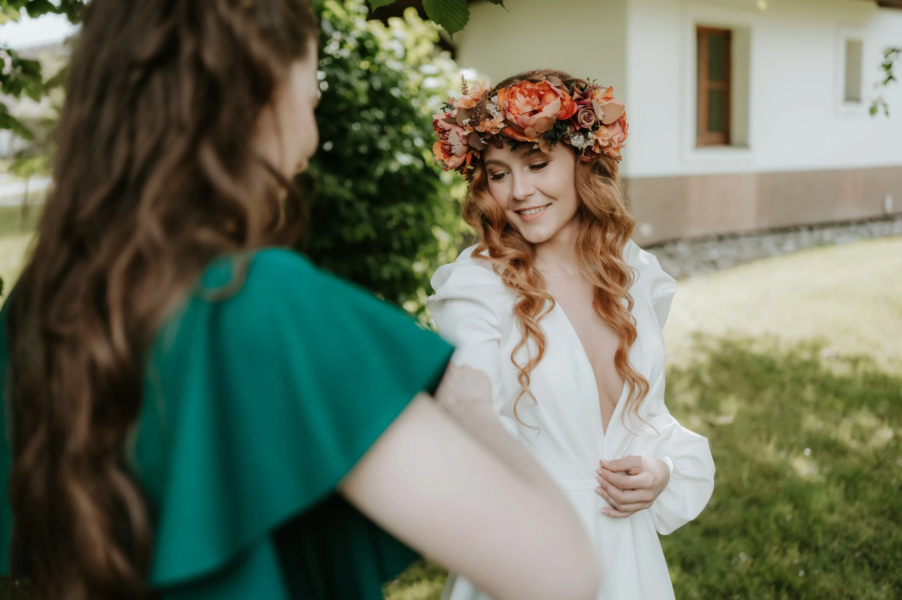 Nevesta sa veselo usmieva s družičkou v zelenej róbe.