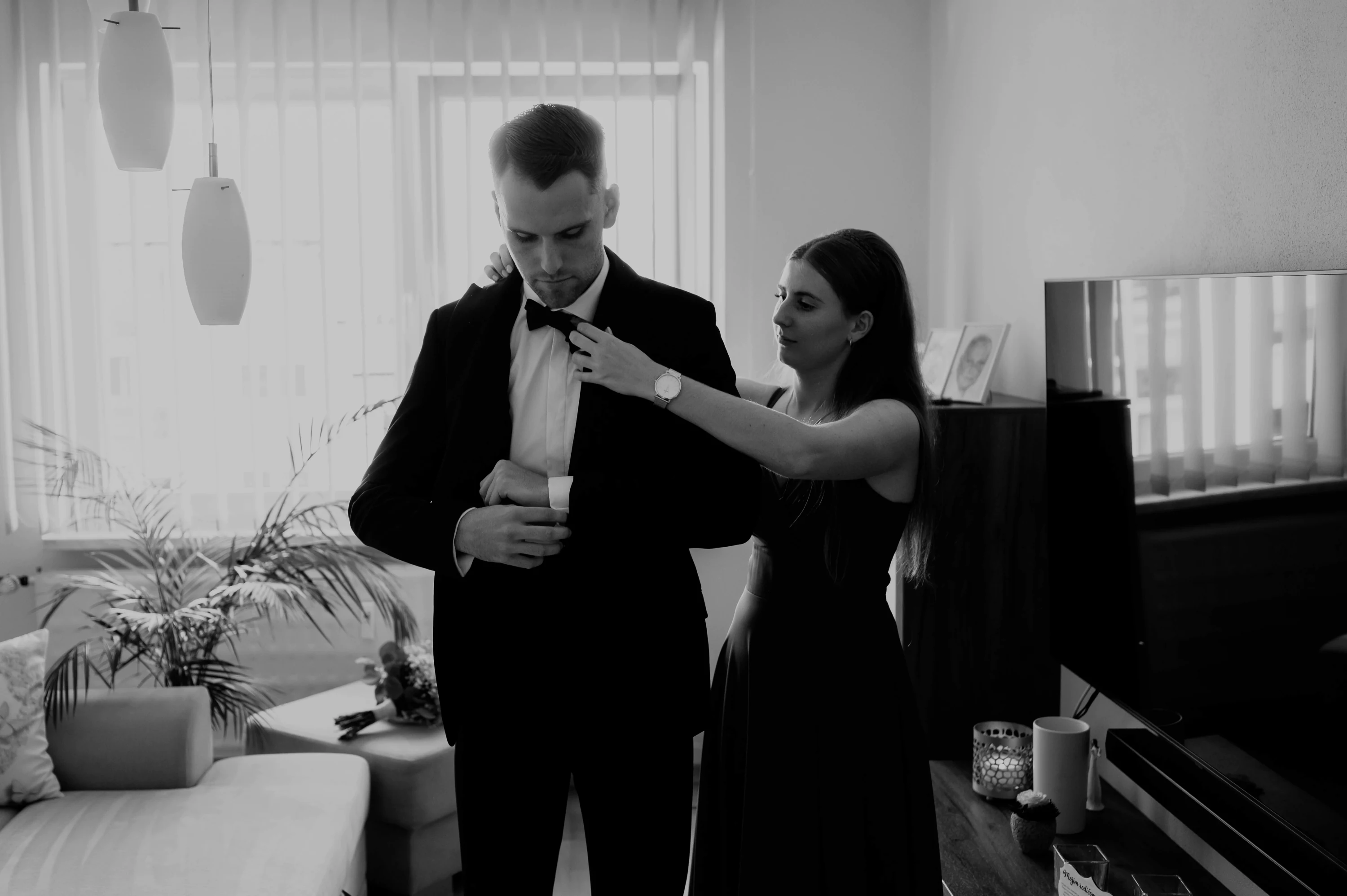 Ženích si upravuje kravatu pred svadbou s pomocou ženy.