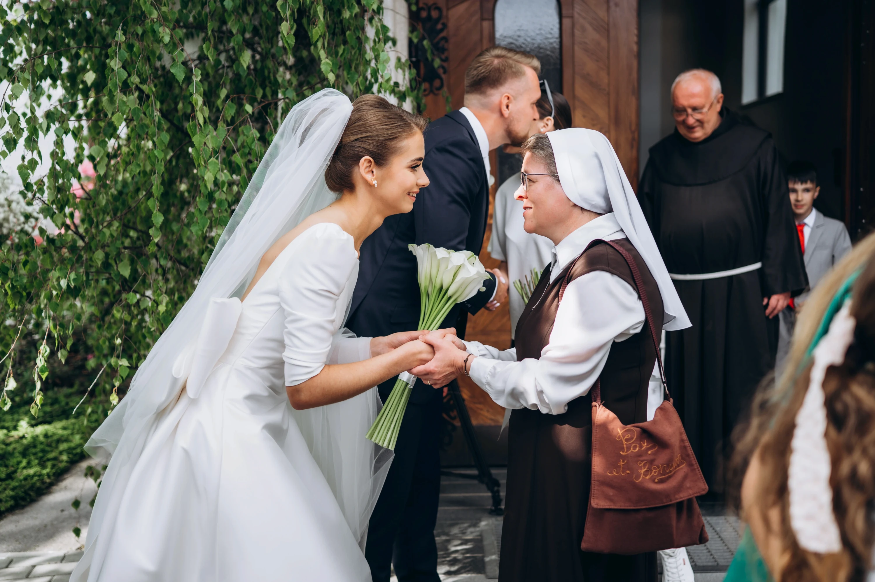Nevesta s kyticou kál sa víta s rehoľnou sestrou pred kostolom.