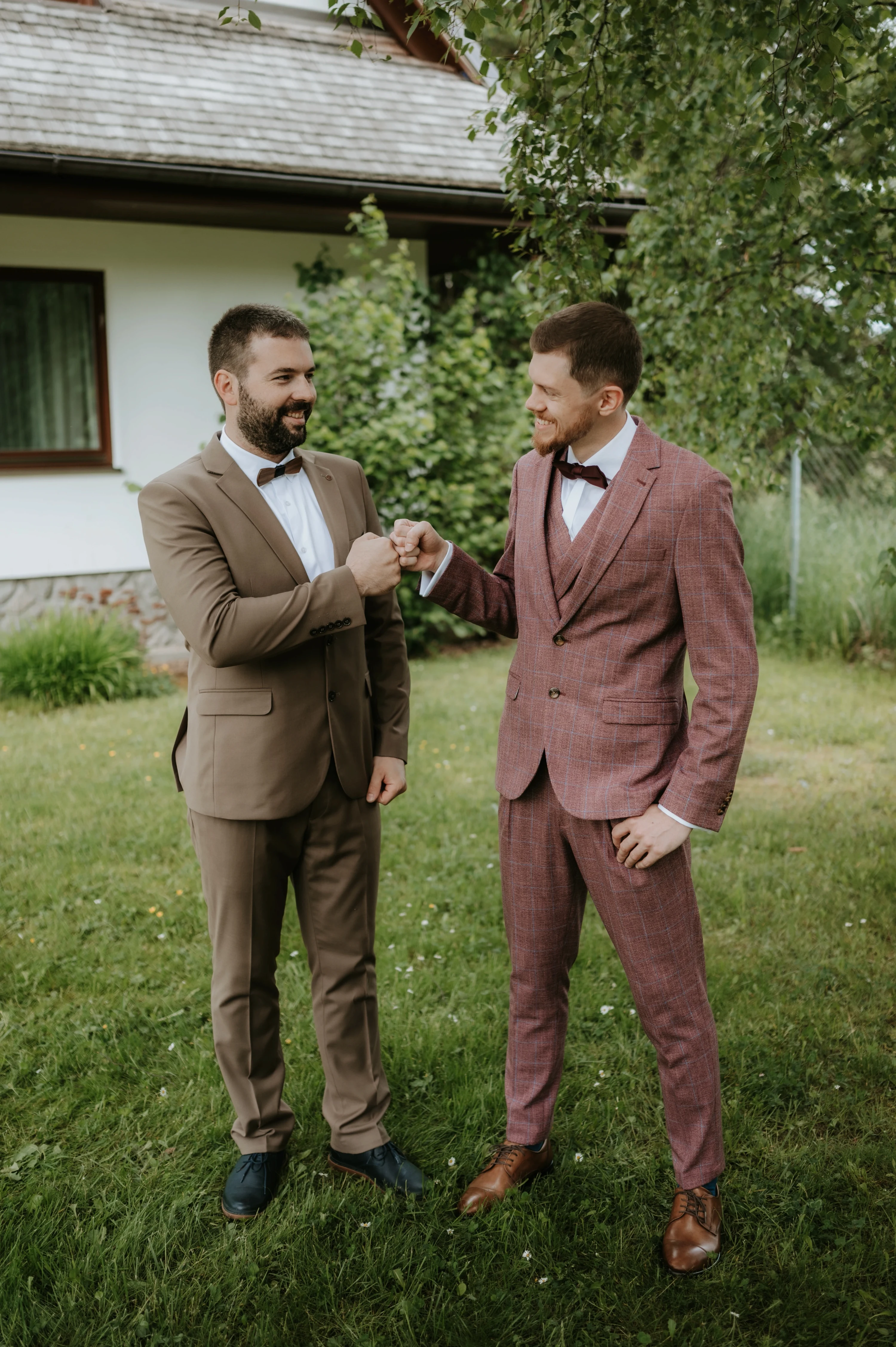 Dvaja muži si podávajú ruku a usmievajú sa pred domom.