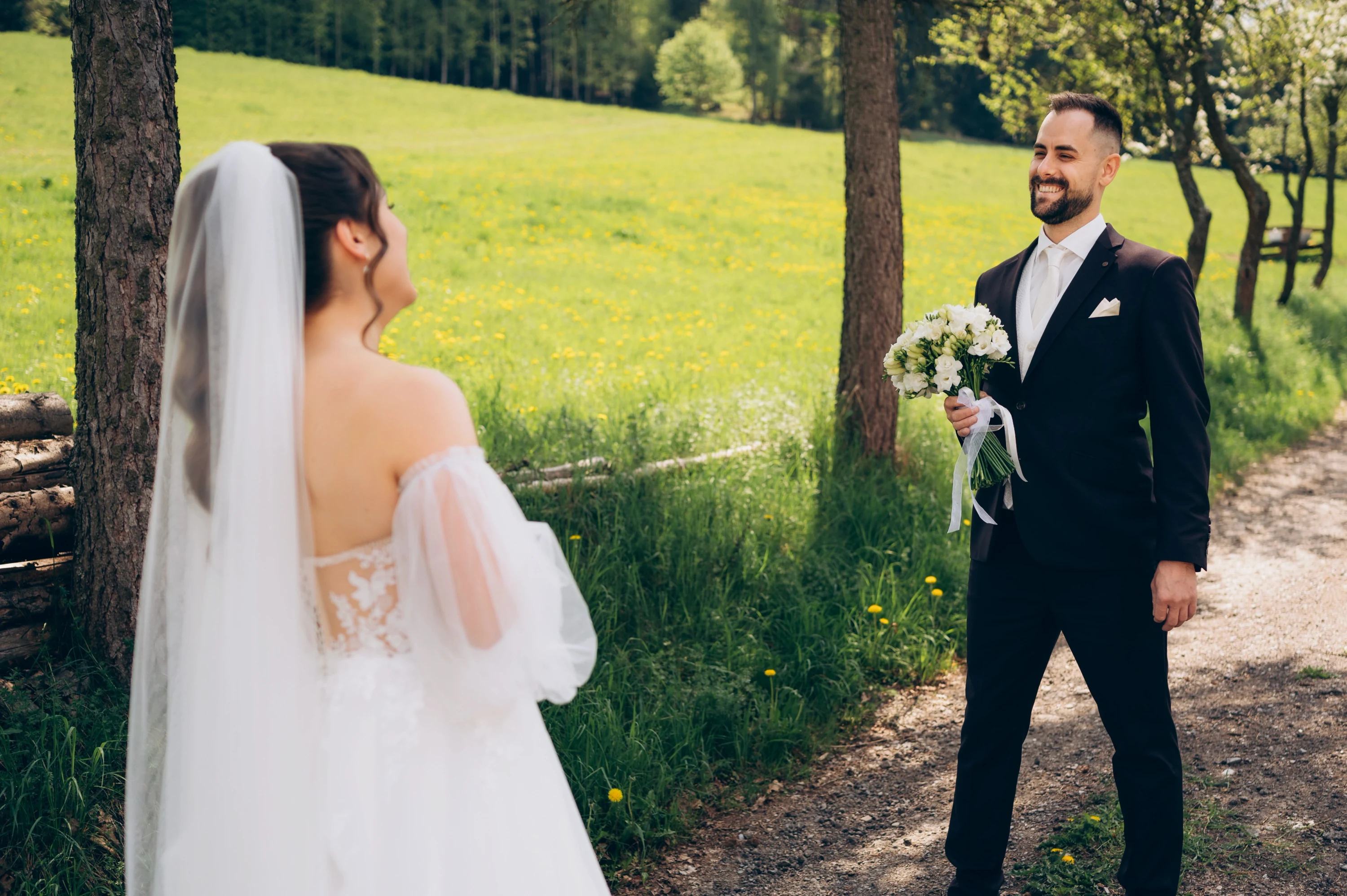 Novomanželia si pozerajú do očí na lesnej ceste v horách.