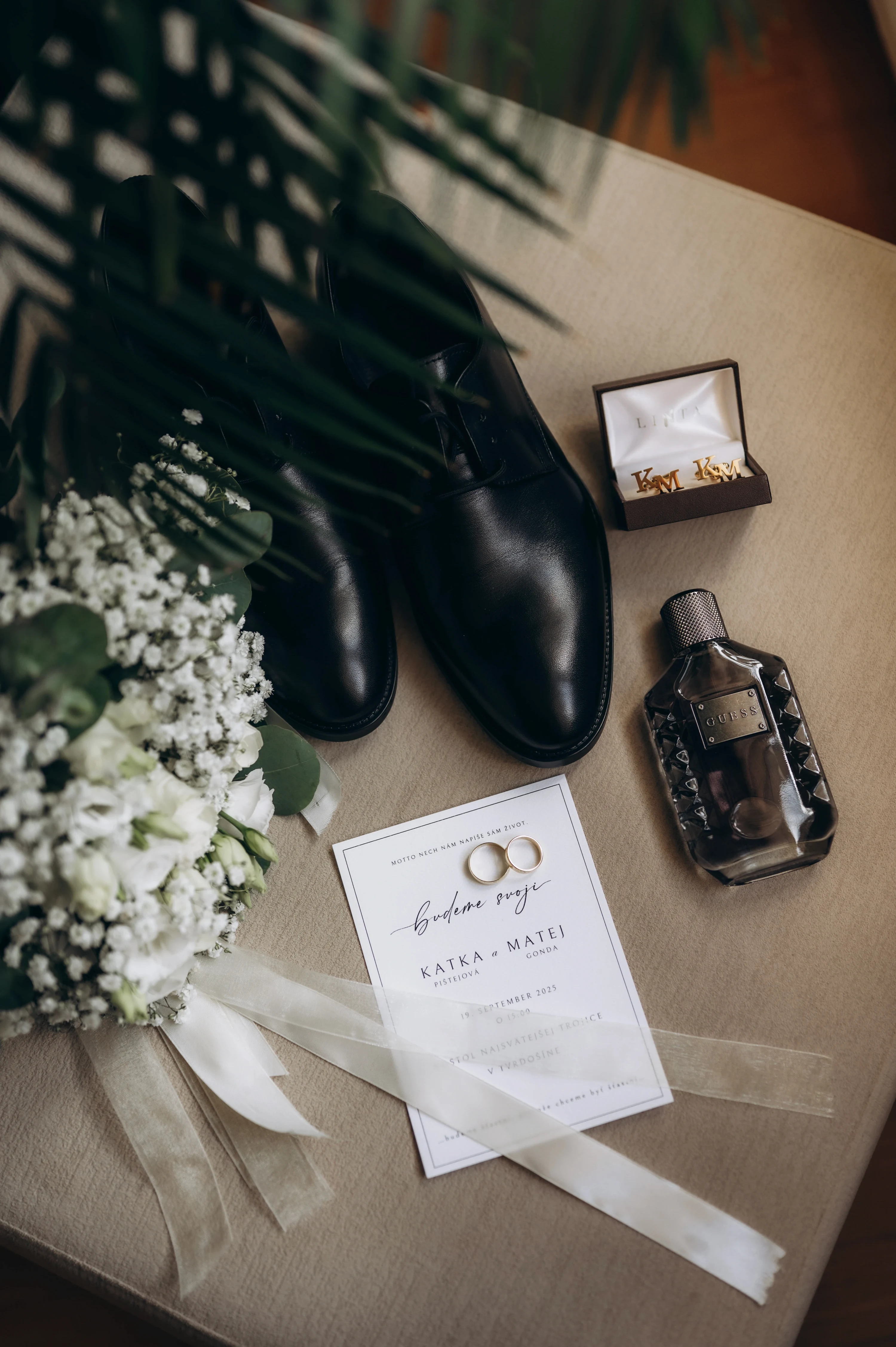 Detaily ženícha - čierne topánky, zlaté prstene a parfum.