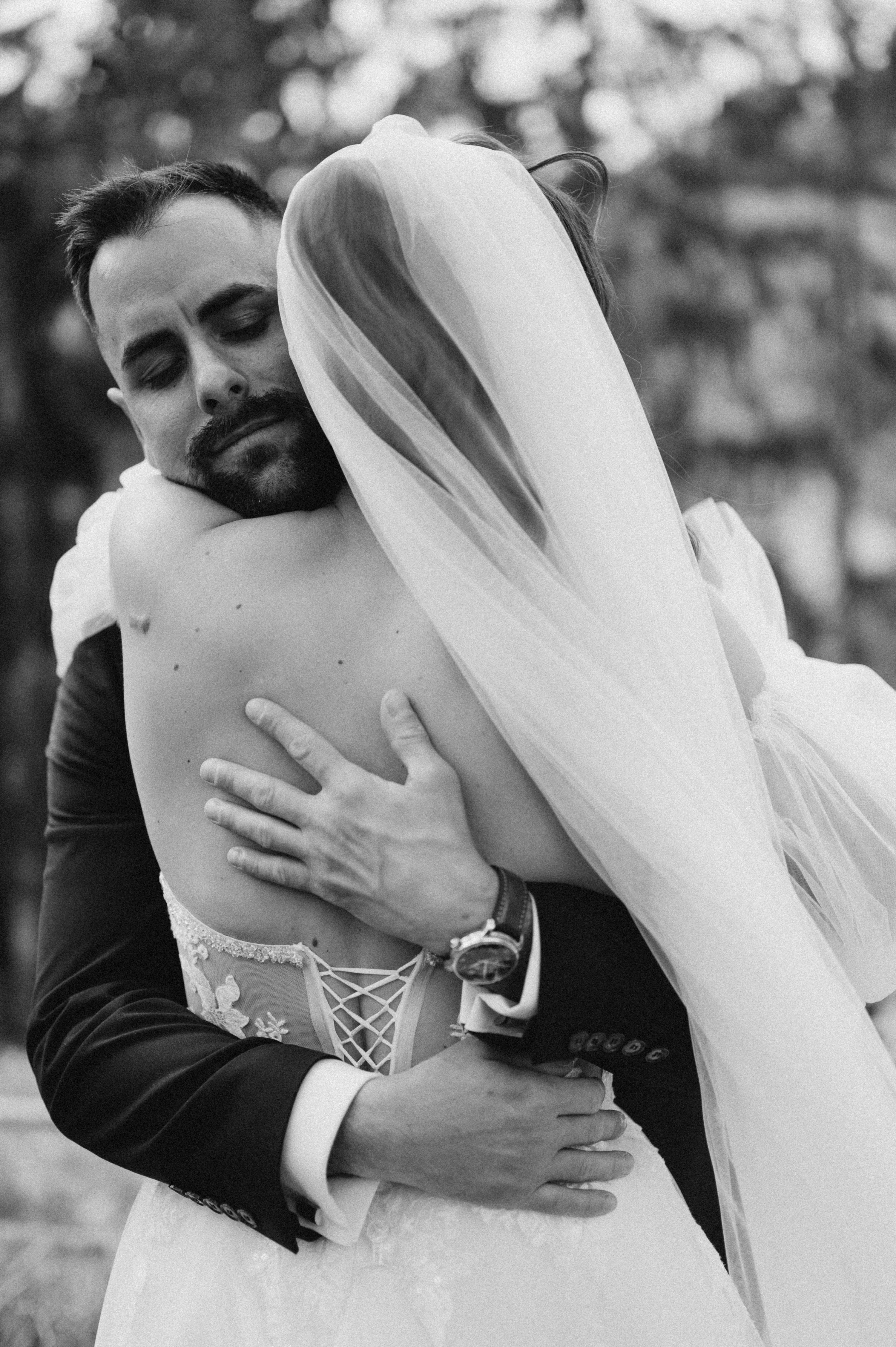 Novomanželia sa nežne objímajú na čiernobielej fotografii v prírode.