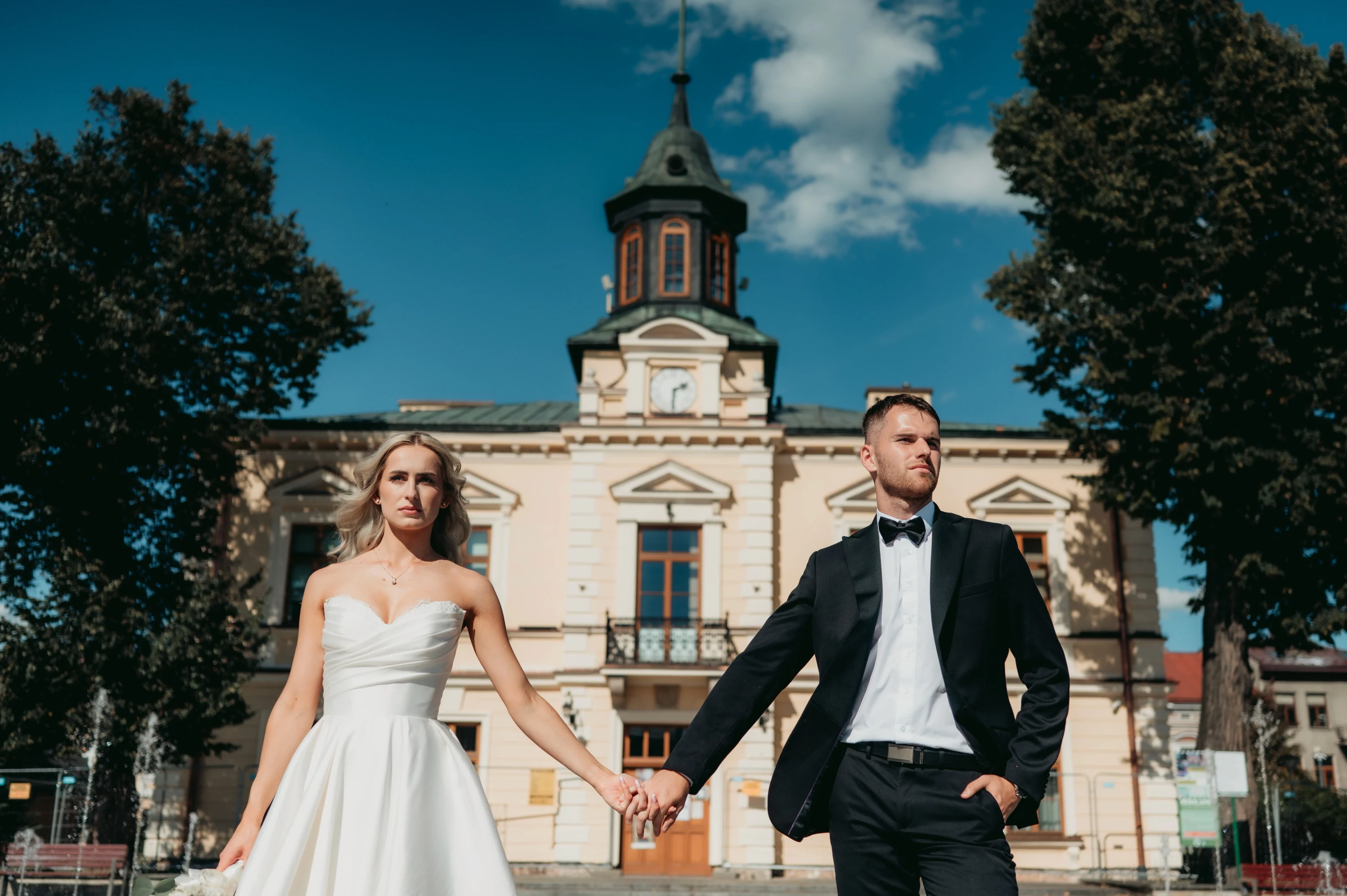 Pár sa drží za ruky pred historickou stavbou.