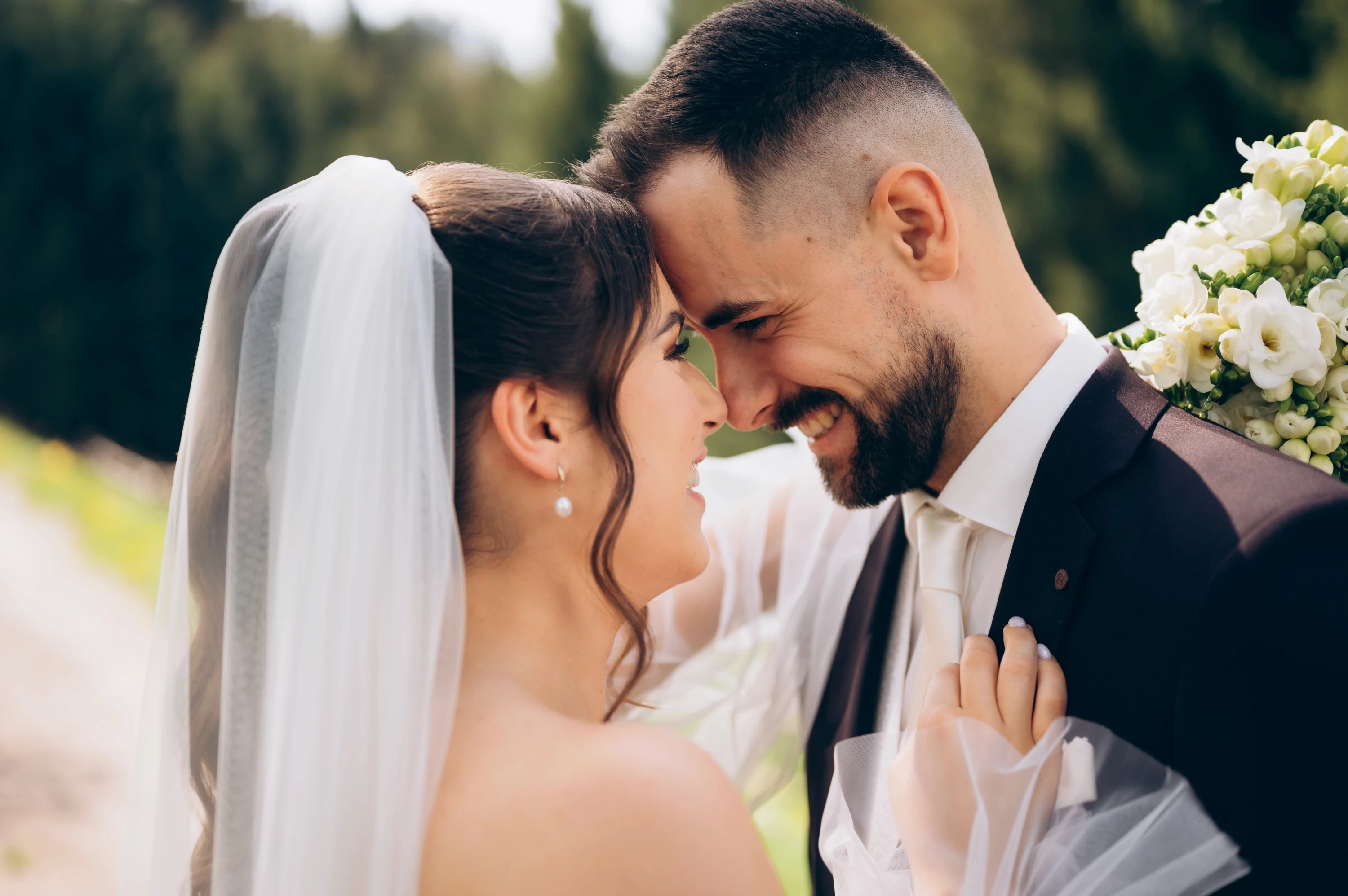 Smiech a šťastie: pár sa usmieva na seba vonku s kvetmi.