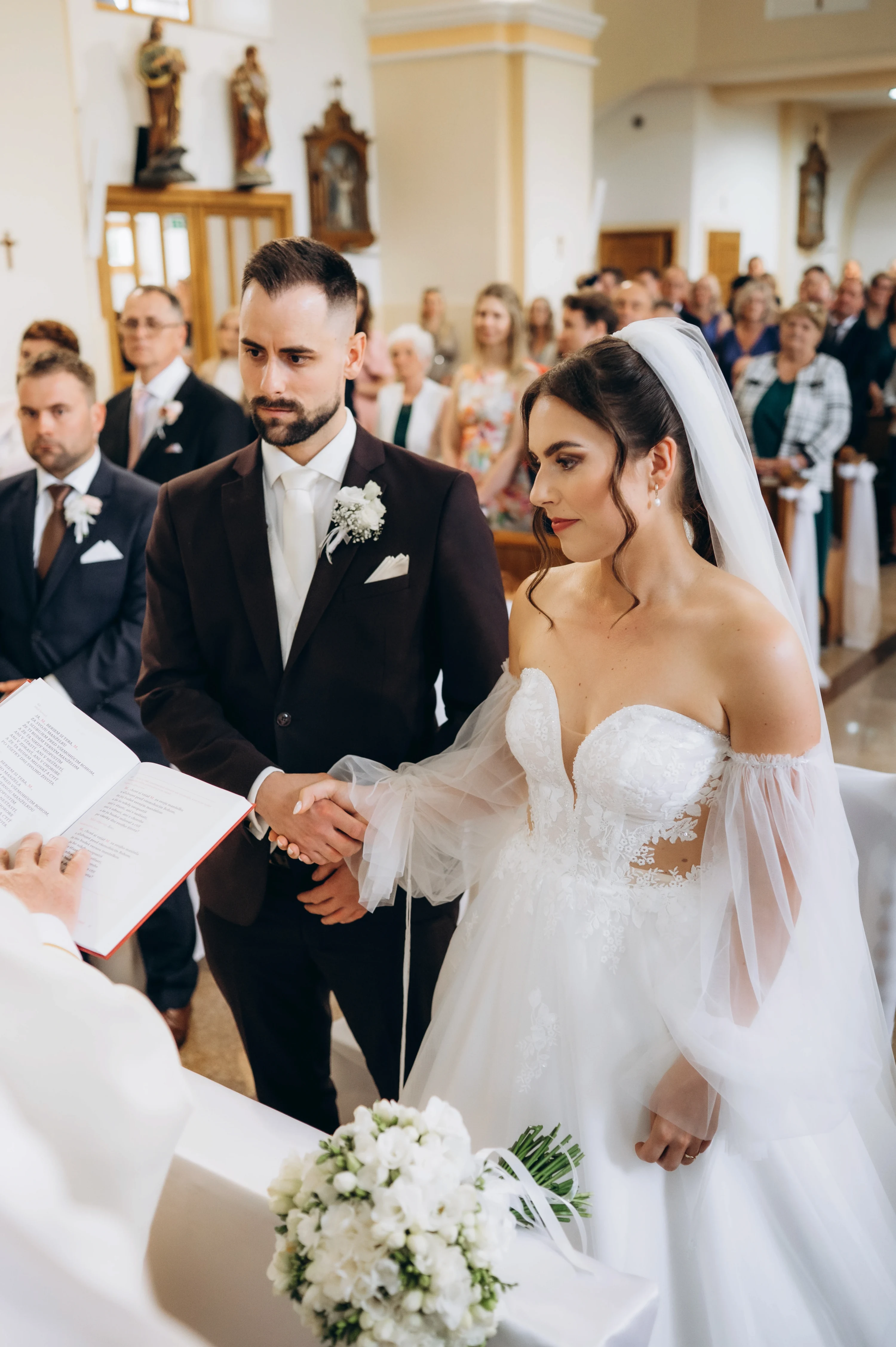 Pri svadobnom obrade sa pár drží za ruky pri oltári pred kňazom.
