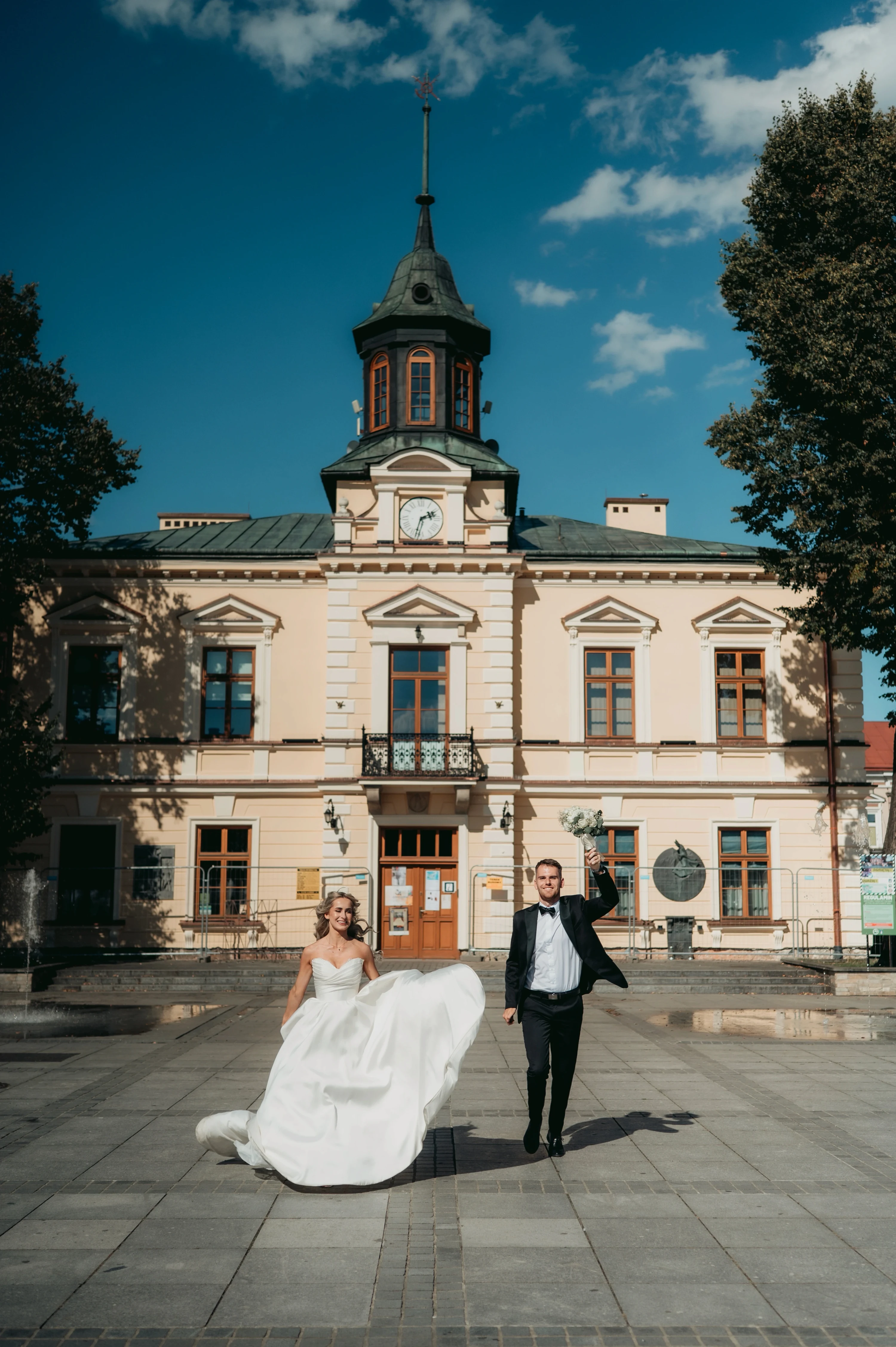Nevesta a ženích sa fotia pred mestskou budovou.