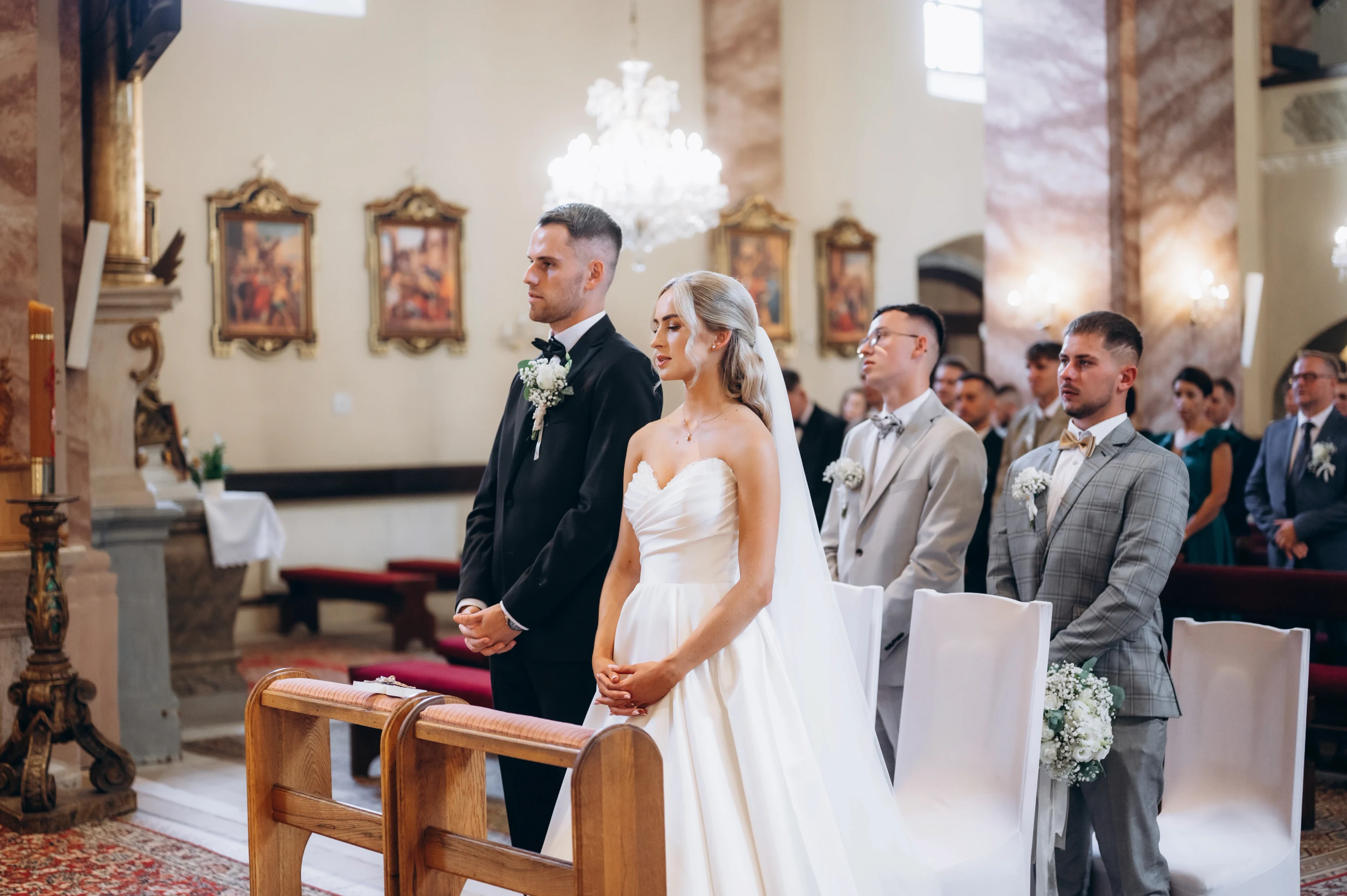 Nevesta a ženích stoja pri oltári so svedkami počas obradu.