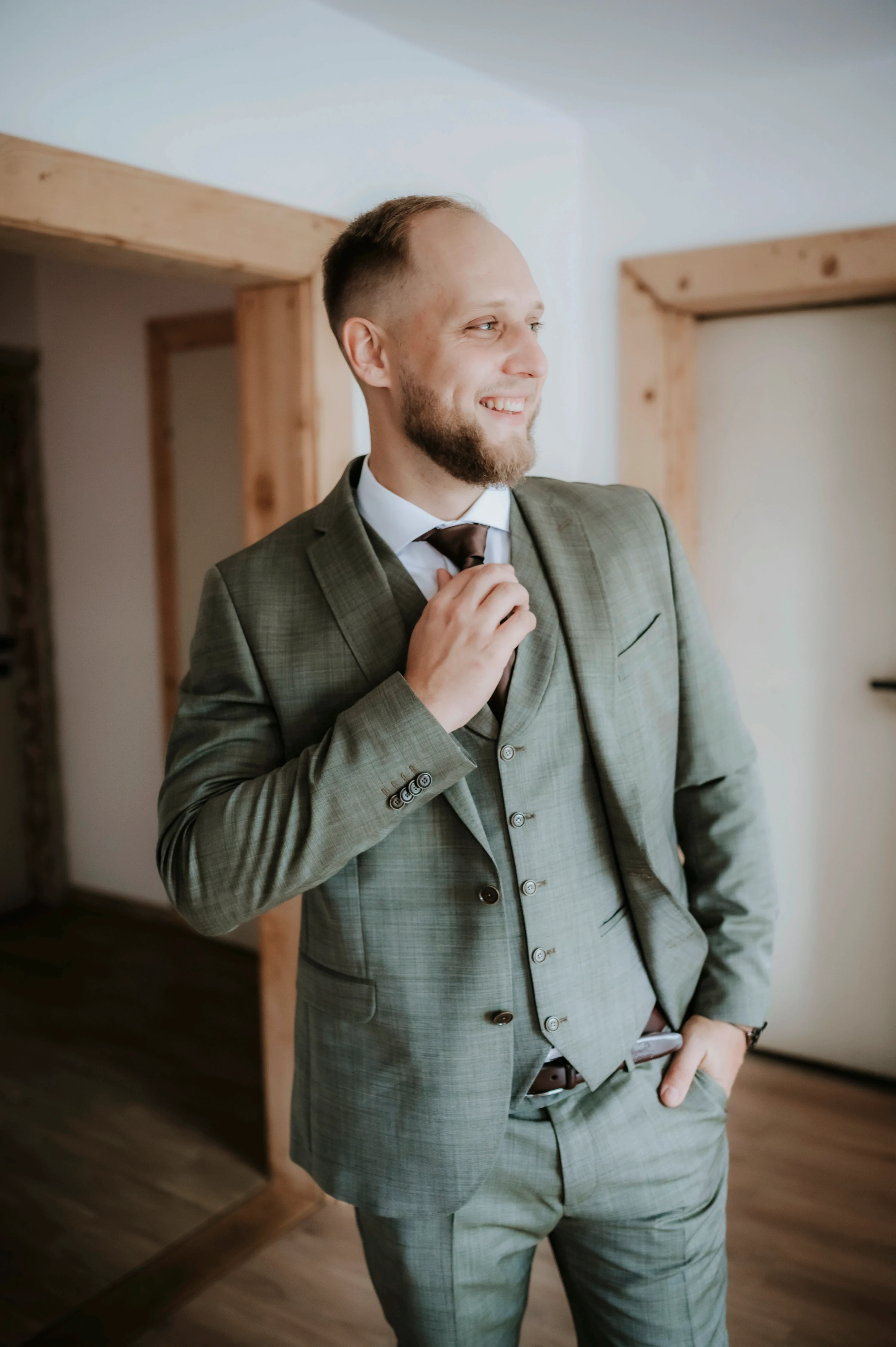 Ženích si upravuje kravatu pred slávnostným obradom v drevenej sále.