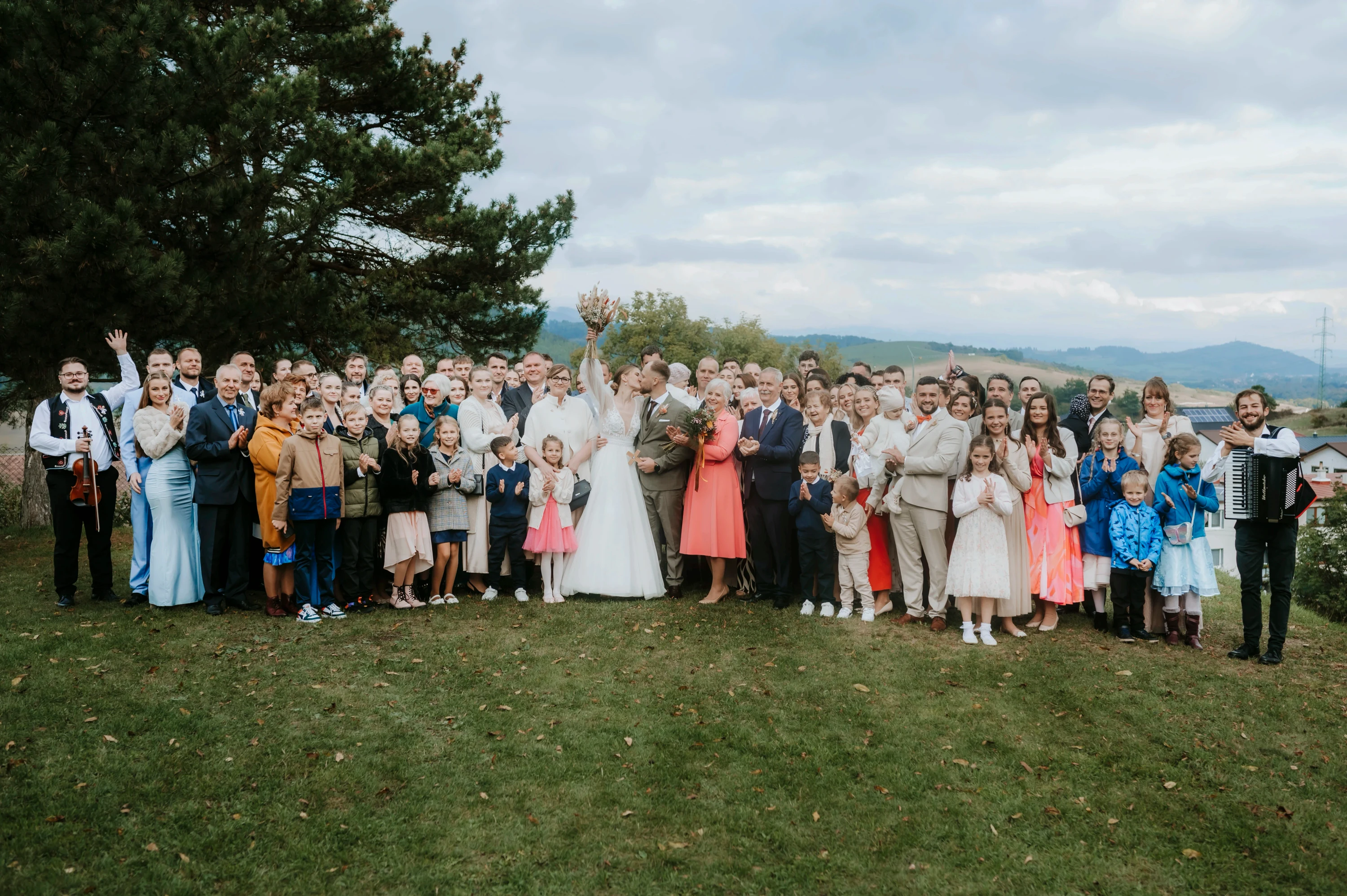 Veľká skupinová fotografia rodiny a hostí na lúke.