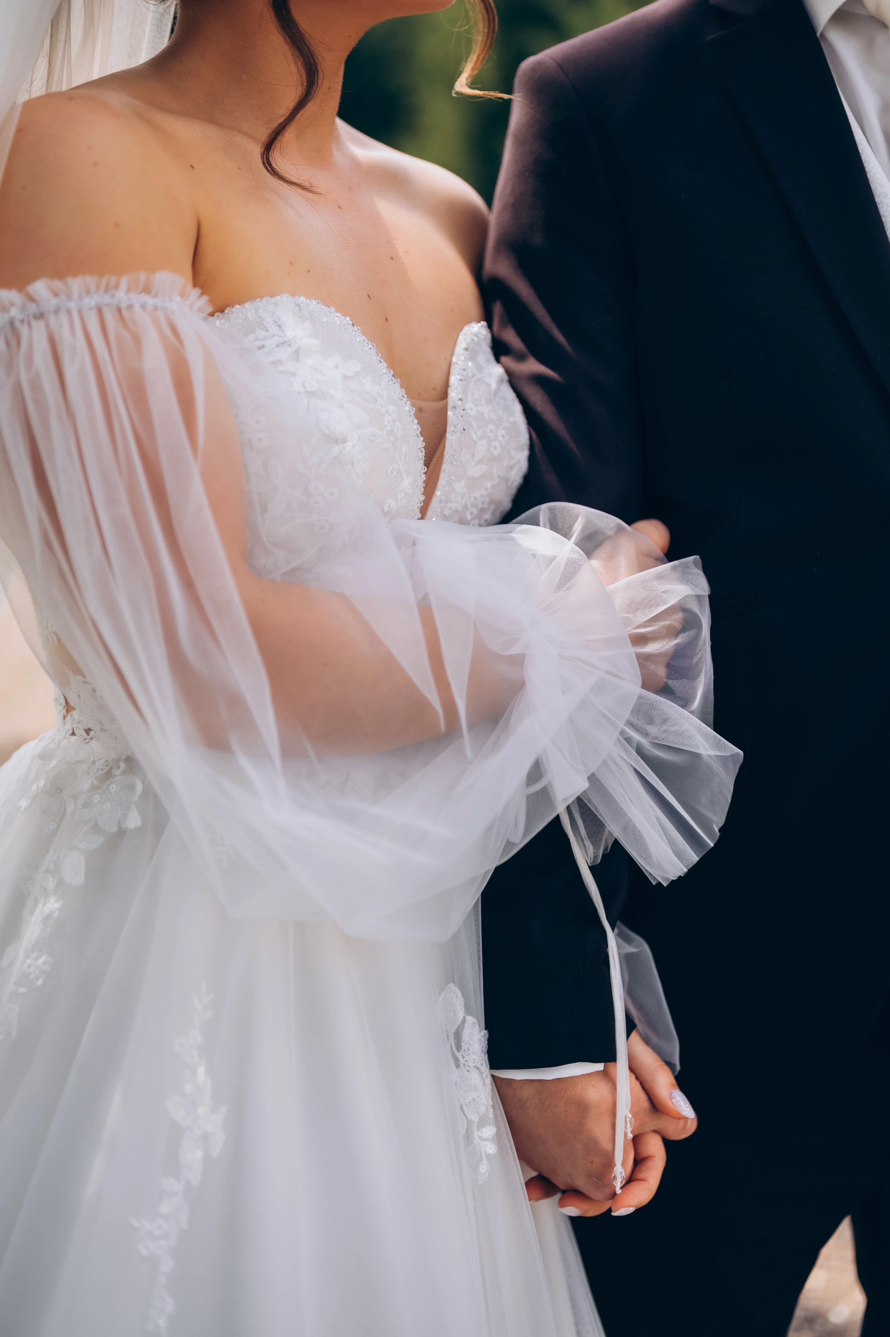 Intímny detail: nevesta sa drží svojho ženícha v prirodzenom svetle.