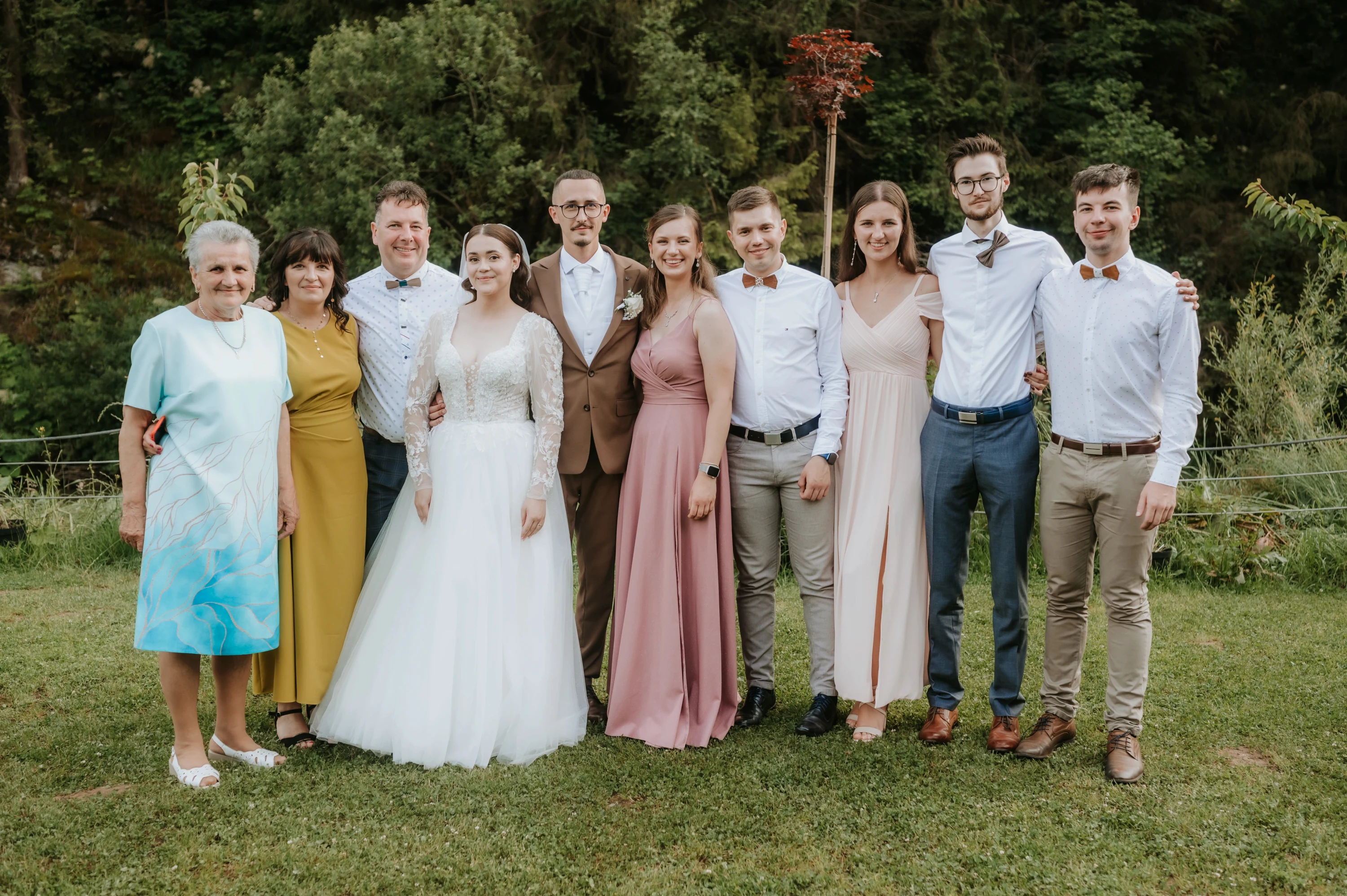 Skupinová fotografia novomanželov s rodinou v záhrade.