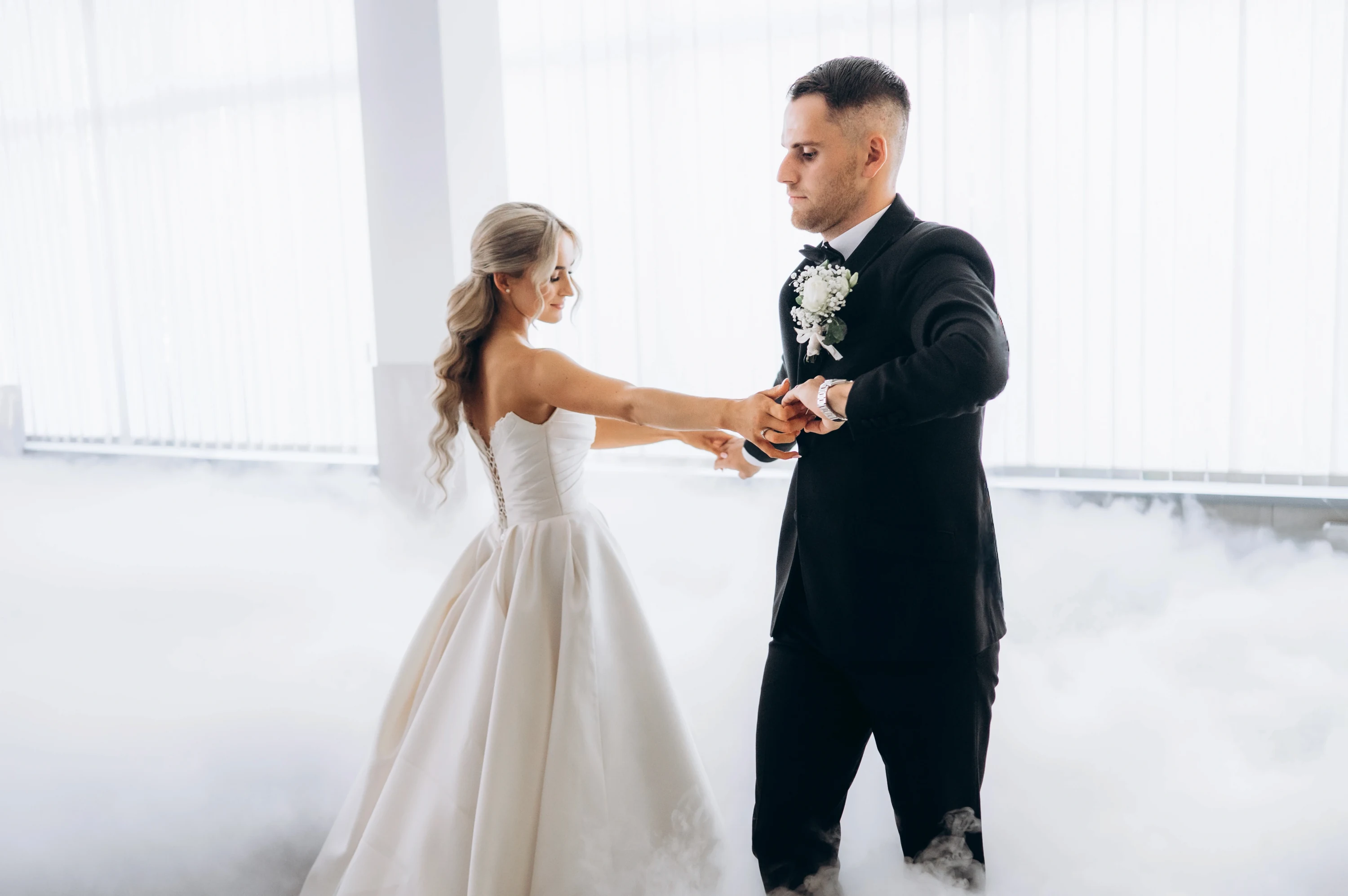 Novomanželia tancujú v presvetlenej sále, po podlahe sa valí nízka hmla.